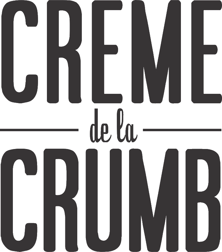 Logo for 'CREME de la CRUMB,' with the words in a bold, modern sans-serif font. 'CREME' and 'CRUMB' are in large capital letters, with 'de la' in a smaller, lowercase script between two horizontal lines, centered above 'CRUMB.' The logo is monochromatic.