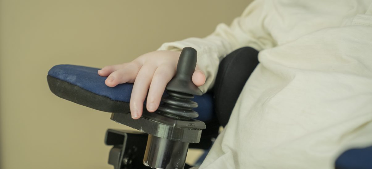 A close-up photo of a child's hand operating their wheelchair