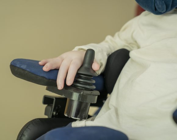A close-up photo of a child's hand operating their wheelchair
