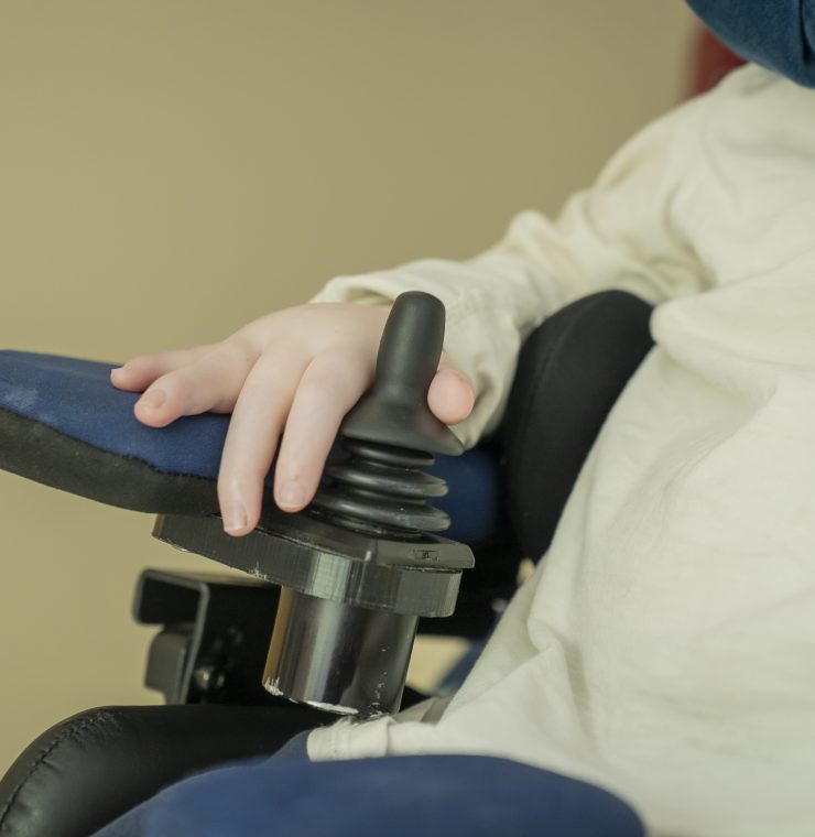 A close-up photo of a child's hand operating their wheelchair