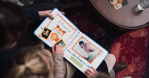 Members of the Van Oosterom family look through their Precious Pictures scrapbook together with Canuck Place Counsellor Natasha Zacher.