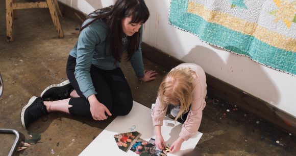 Girl on floor making art with counsellor