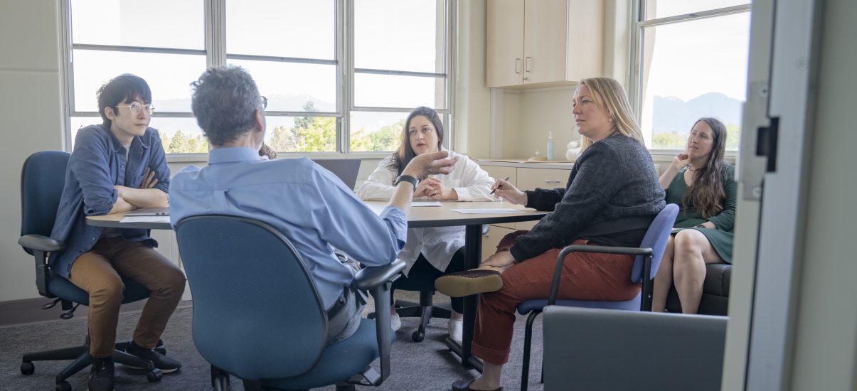 Meeting room with 4 people gathered around a table