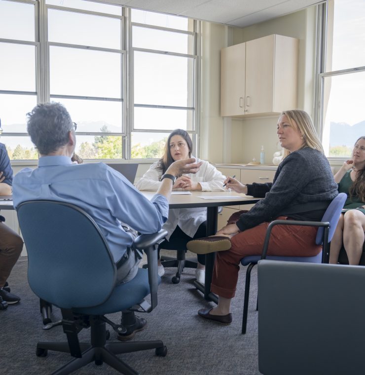 Meeting room with 4 people gathered around a table