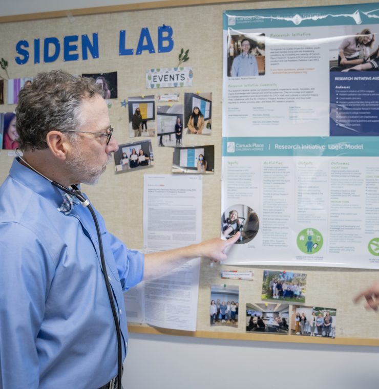 A man gestures toward a research display board labeled