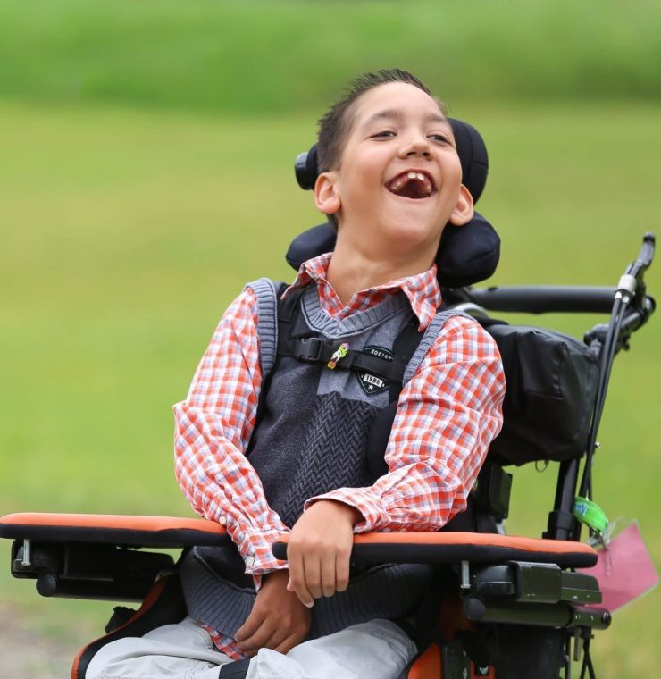 wheelchair using child smiles in a green field